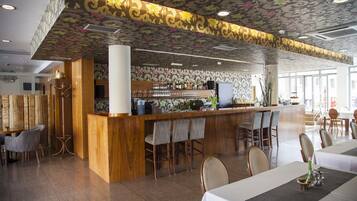 A restaurant with a bar area, wooden bar counter, and several seating options including bar stools and chairs.
