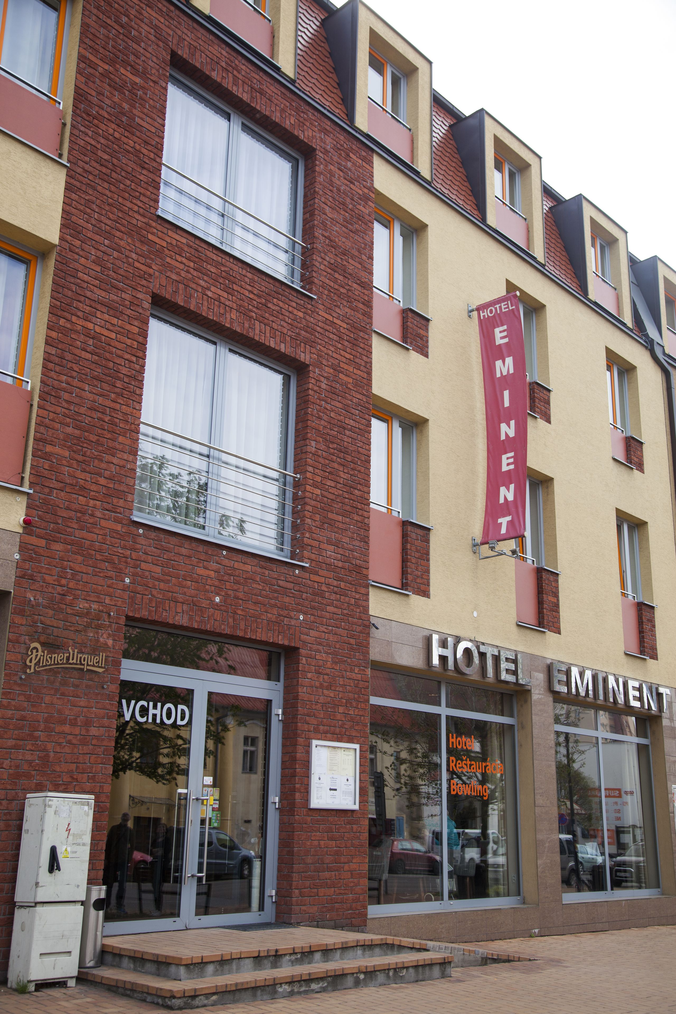 Un hotel con facciata in mattoni rossi, ampie finestre e un vistoso striscione rosso.