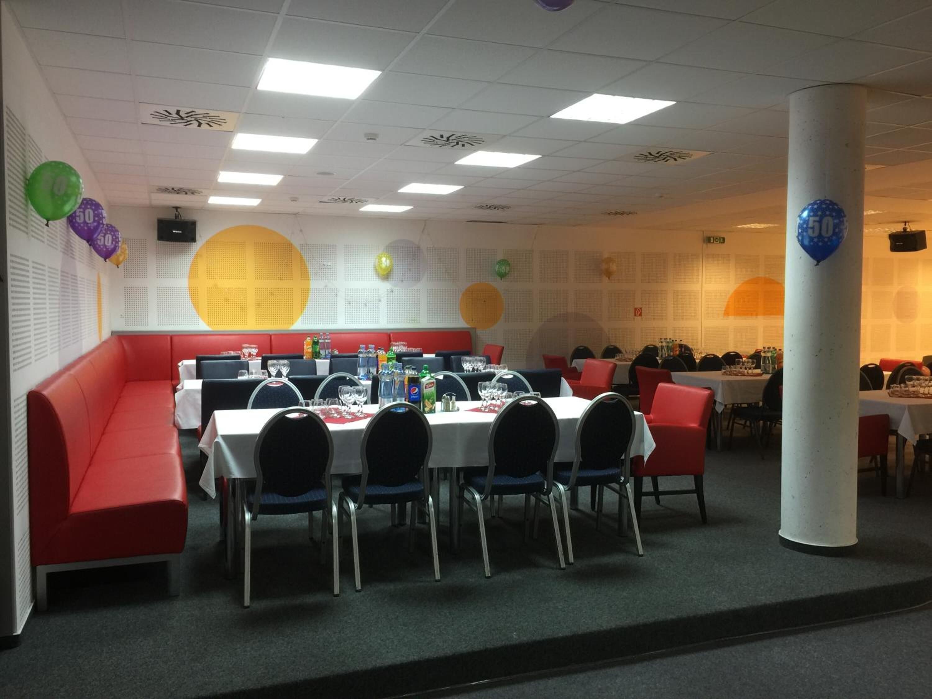 A conference room with round tables, chairs, and a red sofa.