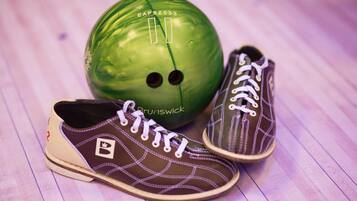 Una bola de boliche verde y dos zapatos sobre un piso de madera.