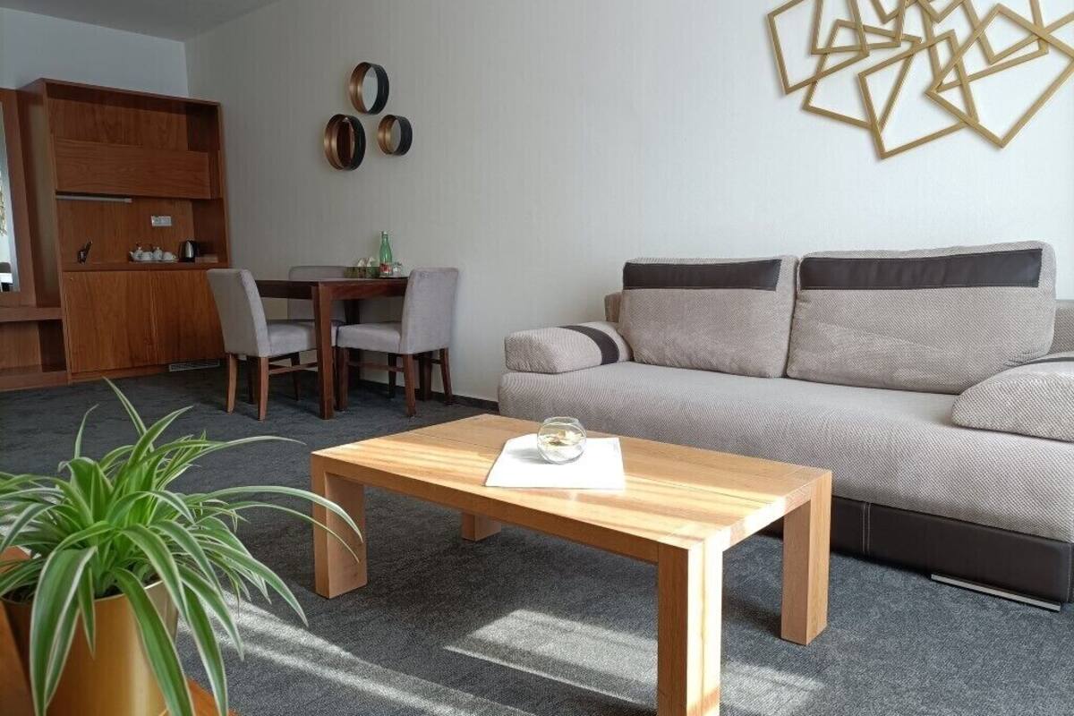 Una sala de estar moderna con una mesa de centro de madera, un sofá gris y un comedor con un aparador de madera y sillas.