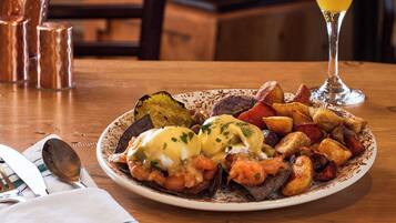 A breakfast plate with eggs benedict, potatoes, and vegetables on a table.