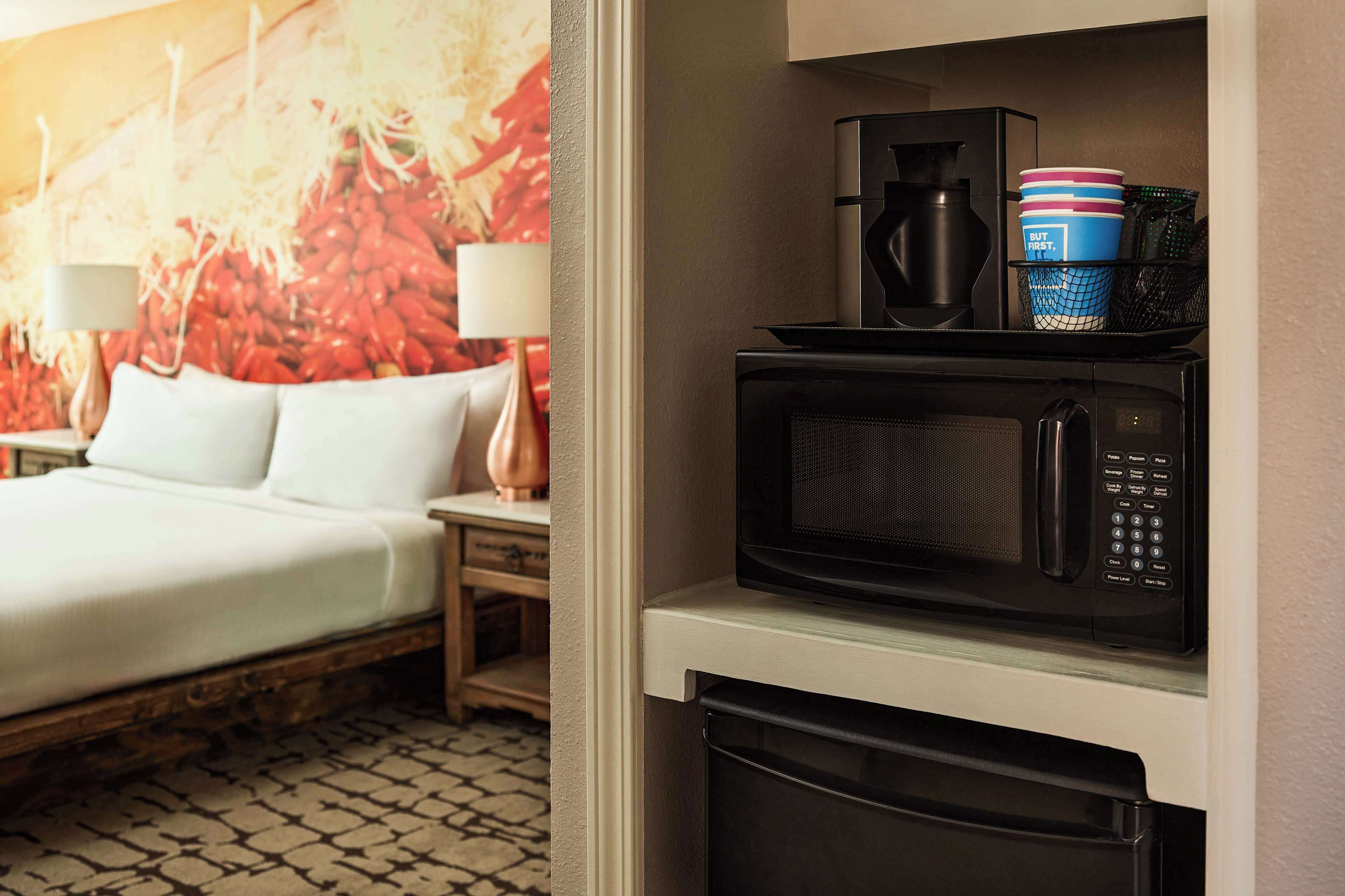 A hotel room with a bed, a microwave, and a coffee maker on the counter.