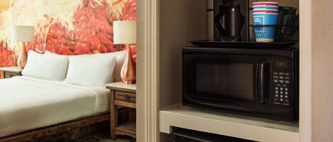 A hotel room with a bed, a microwave, and a coffee maker on the counter.
