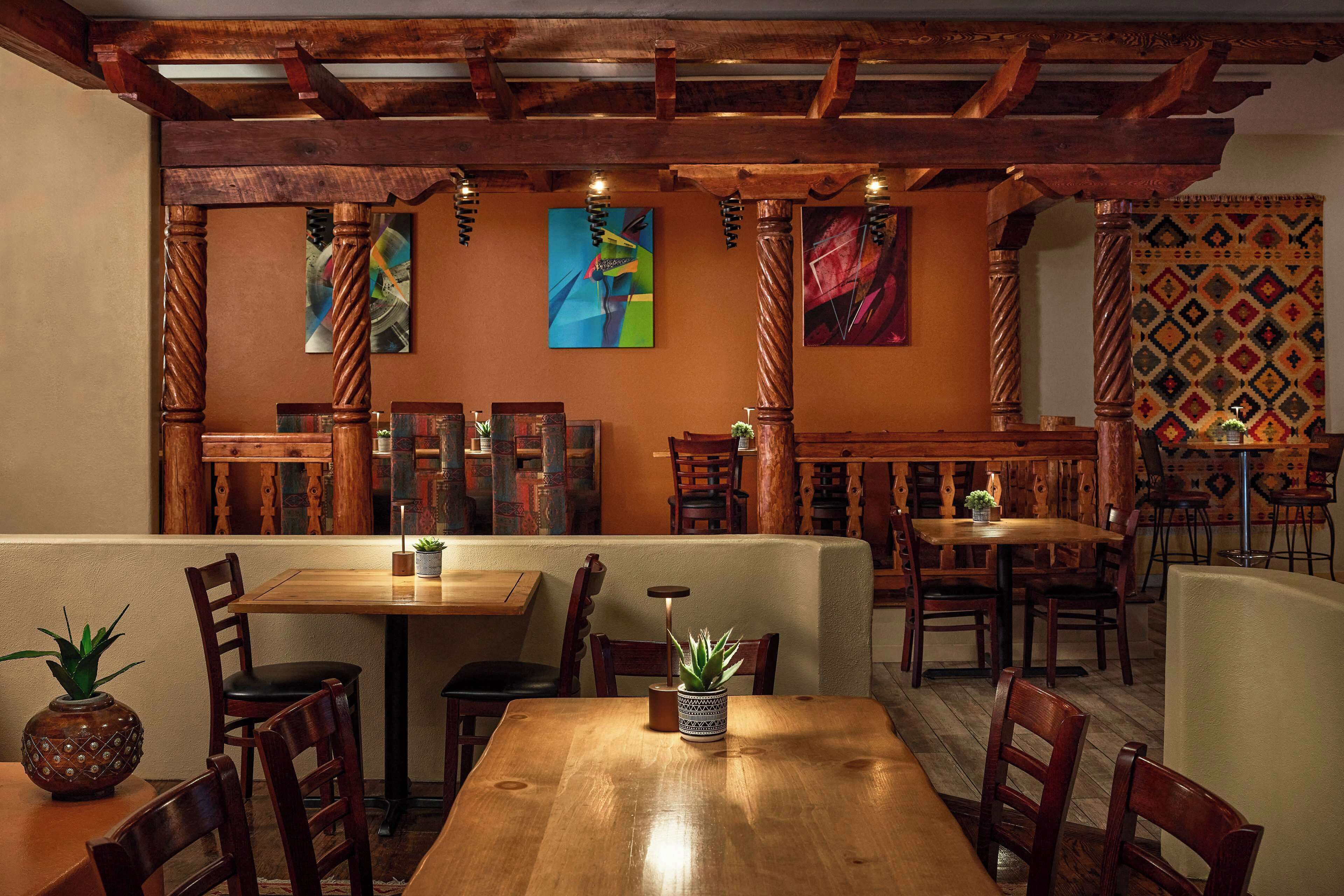 Ein Restaurant mit Holztischen und -stühlen, einer Holzzahlendecke und Wandbildern.