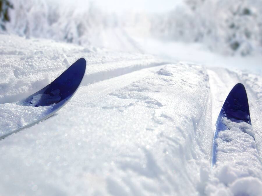 A snowy path with two blue skis.