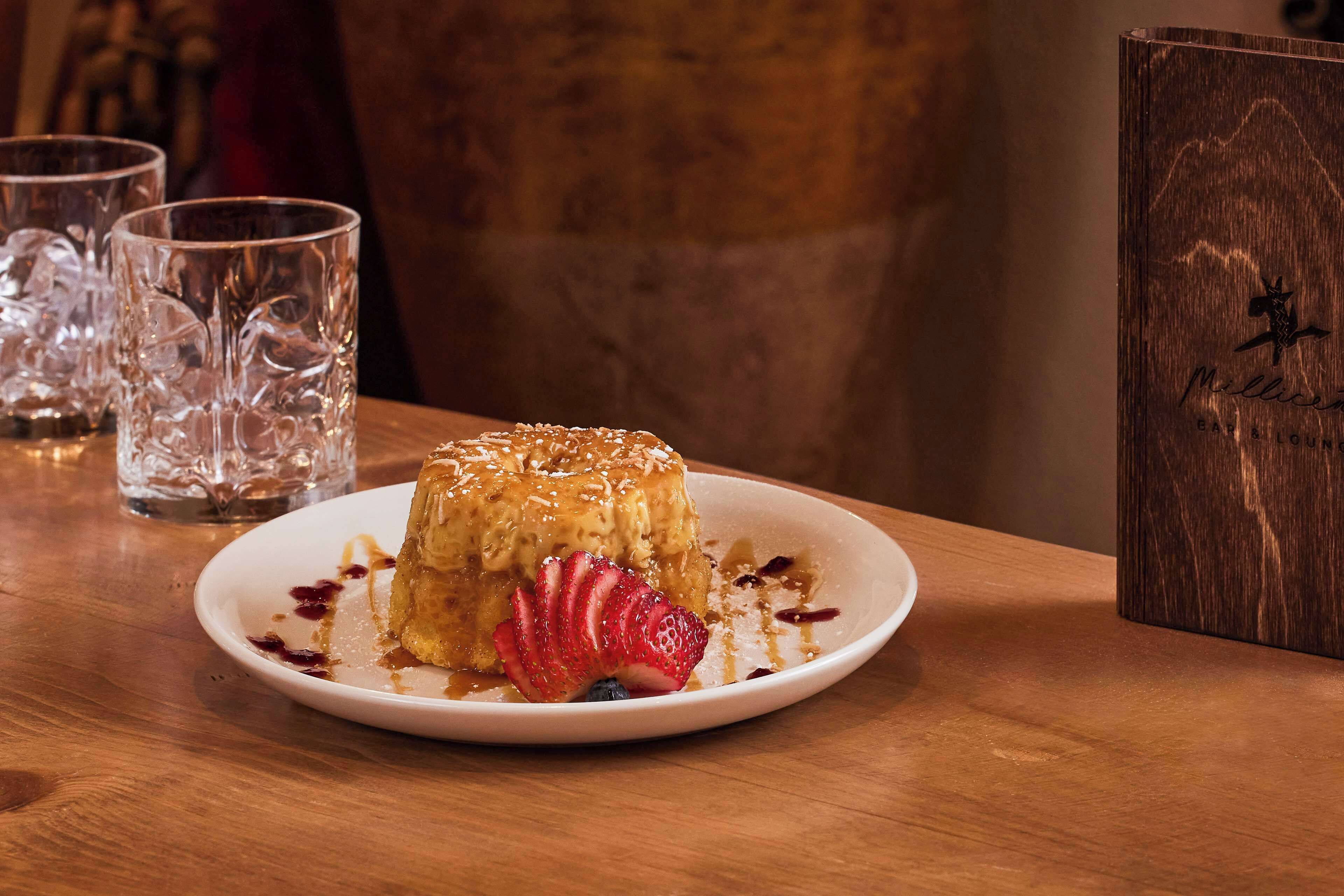 Un dessert présenté sur une assiette, avec une table en bois et un menu à proximité.