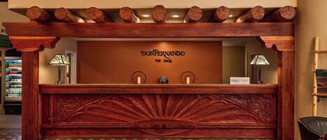 A reception desk with a carved wooden design, a check-in counter, and a tiled floor.