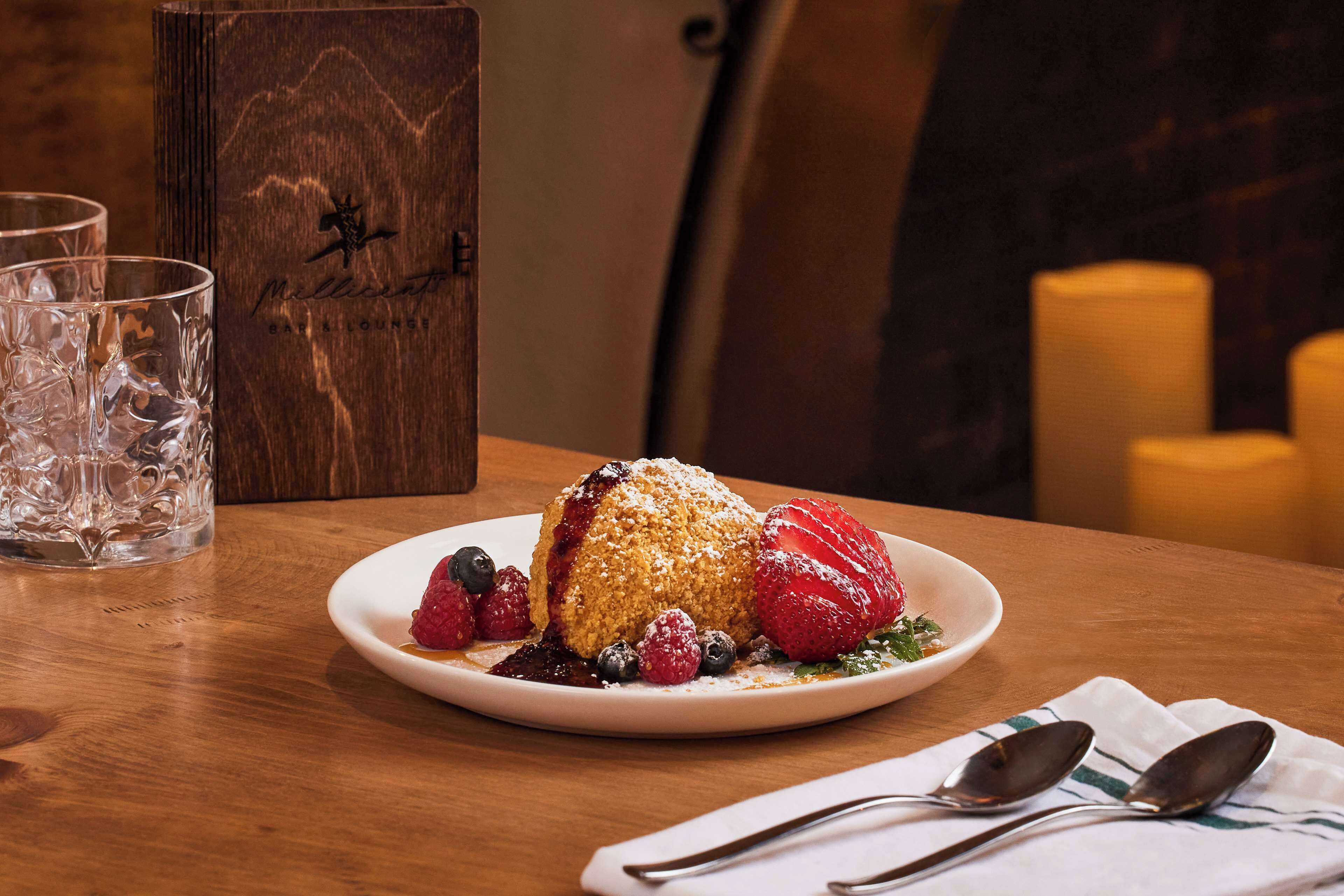A dessert plate with a cake, strawberries, and blueberries on a wooden table.