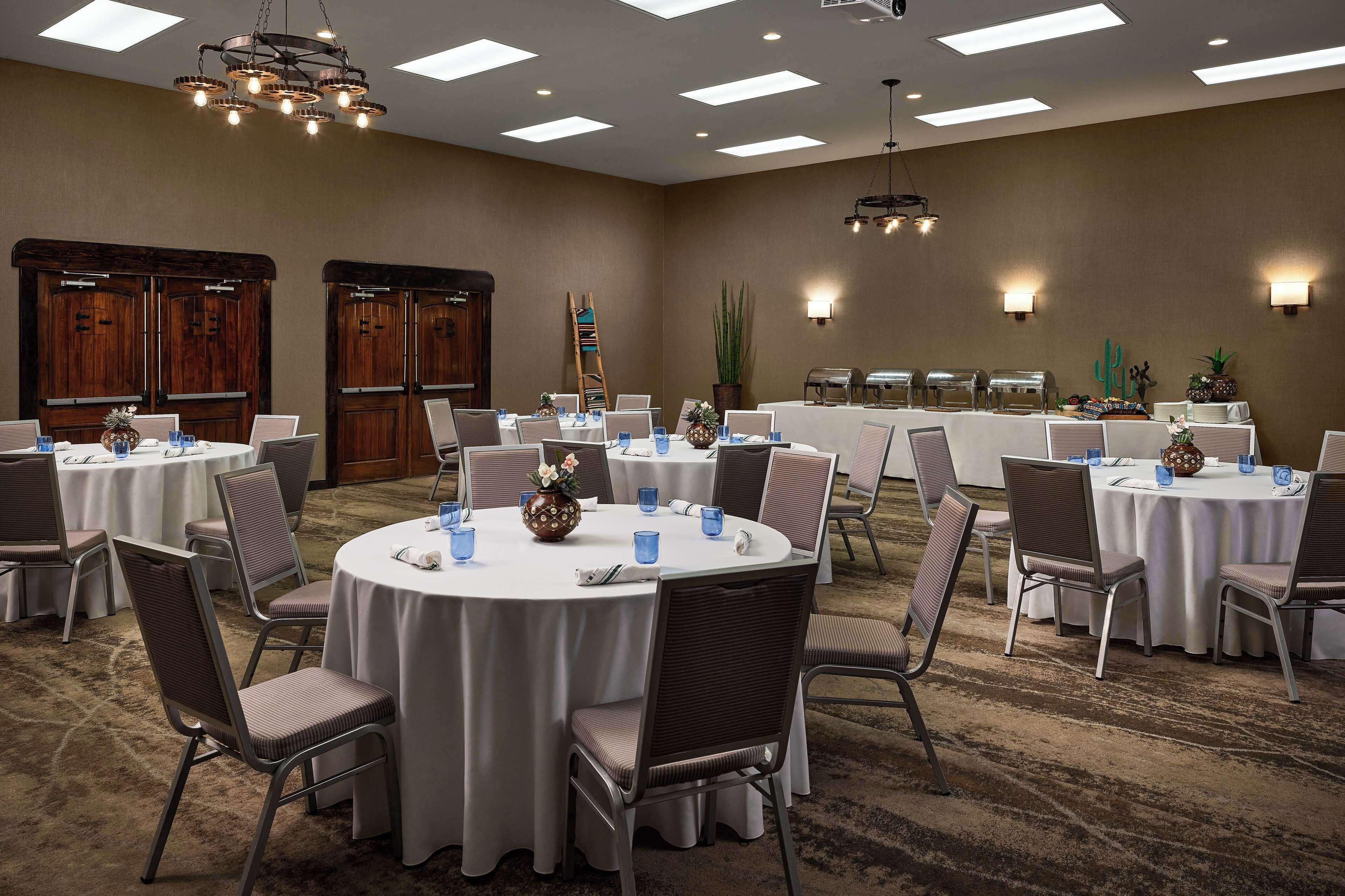 A conference room with round tables, chairs, and a buffet setup.
