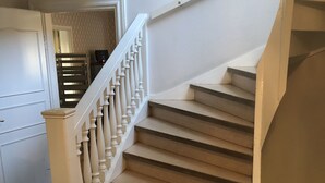 Een trap met witte balustrades en beige treden die uitkomen op een plateau.