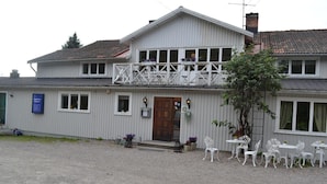 Een gebouw met twee verdiepingen, een balkon, terras en een bord waarop een bedrijf is aangegeven.