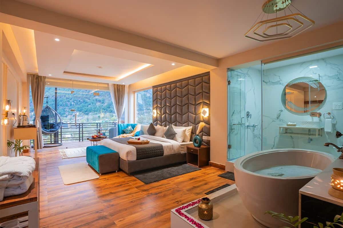 Un dormitorio moderno con una cama grande, un baño con paredes de vidrio y vistas al exterior.