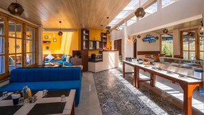 A modern interior with a blue sofa, wooden ceiling, and a kitchen area with a dining table. -  Moustache Manali (Manali)
