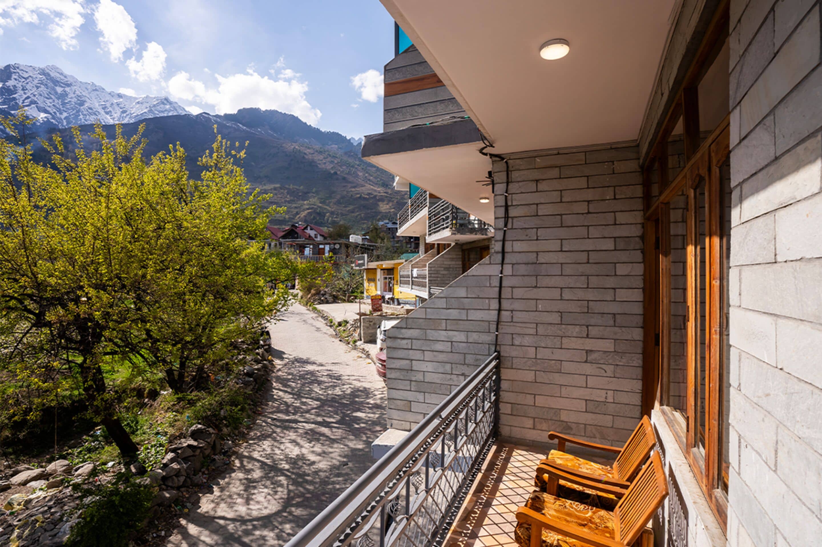 A balcony with a wooden bench, a stone wall, and a mountain view.