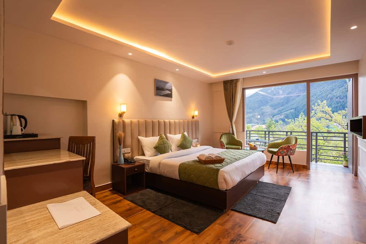 Una habitación de hotel moderna con una cama grande, un escritorio y un balcón con vistas a la montaña.