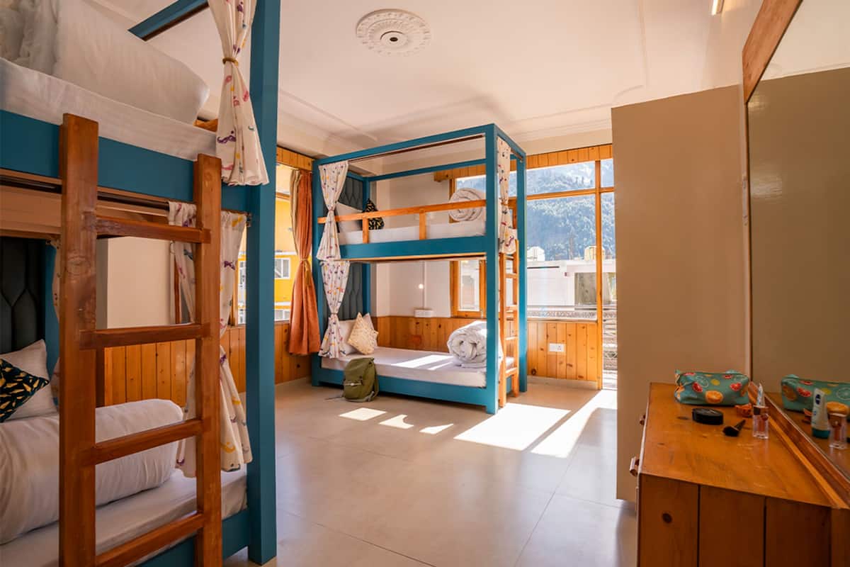 Una habitación con literas, un escritorio de madera y una ventana con vistas a montañas.