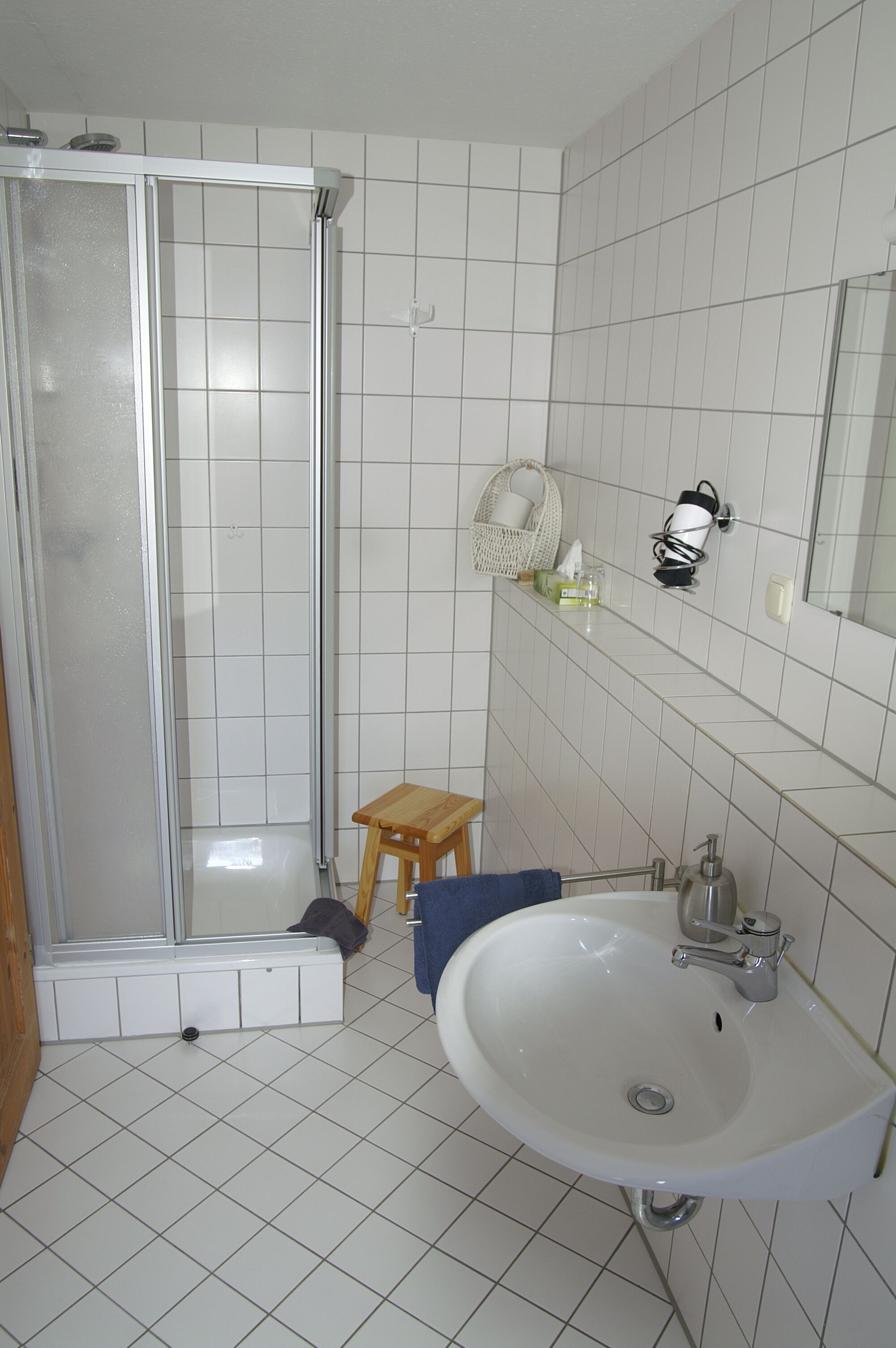 Une salle de bain avec une douche, un lavabo et des murs carrelés.