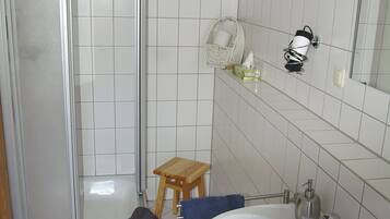Une salle de bain avec une douche, un lavabo et des murs carrelés.