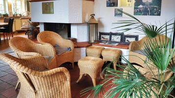 A room with wicker furniture, a fireplace, and wall-mounted pictures.