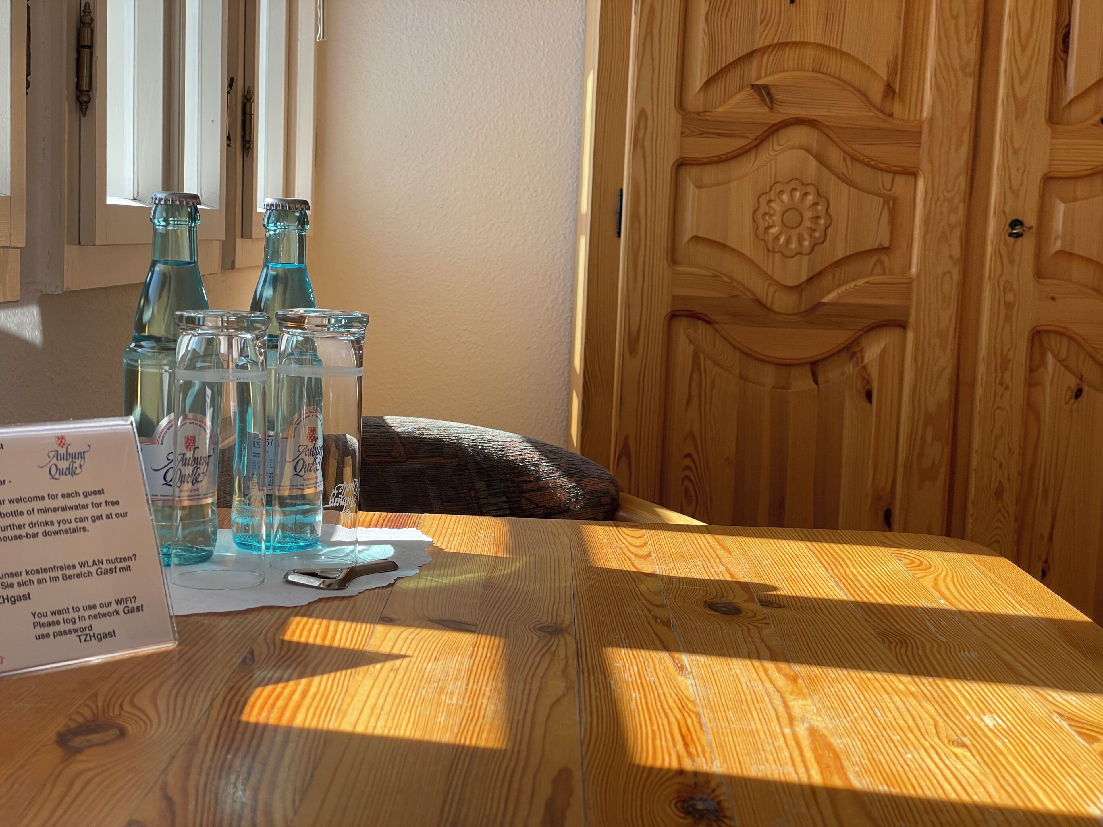 A wooden table with bottles, a sign, and a door with a decorative panel.
