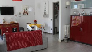 Ein modernes Wohnzimmer mit einem grauen Sofa, einer rot gepunkteten Decke, einem Essbereich mit einem gelben Tisch und einem roten Schrank.