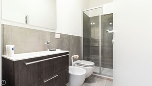 Une salle de bain moderne avec un grand miroir, un meuble-lavabo, des toilettes et une douche à parois de verre.