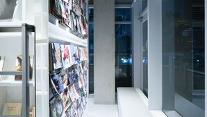 Un interior modern amb una pared de revistes, una banca i una porta de vidre que dona a un balcó.