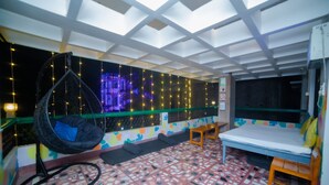 Een kamer met een hangstoel, een bed en een kleurrijke muur met een geometrisch patroon.