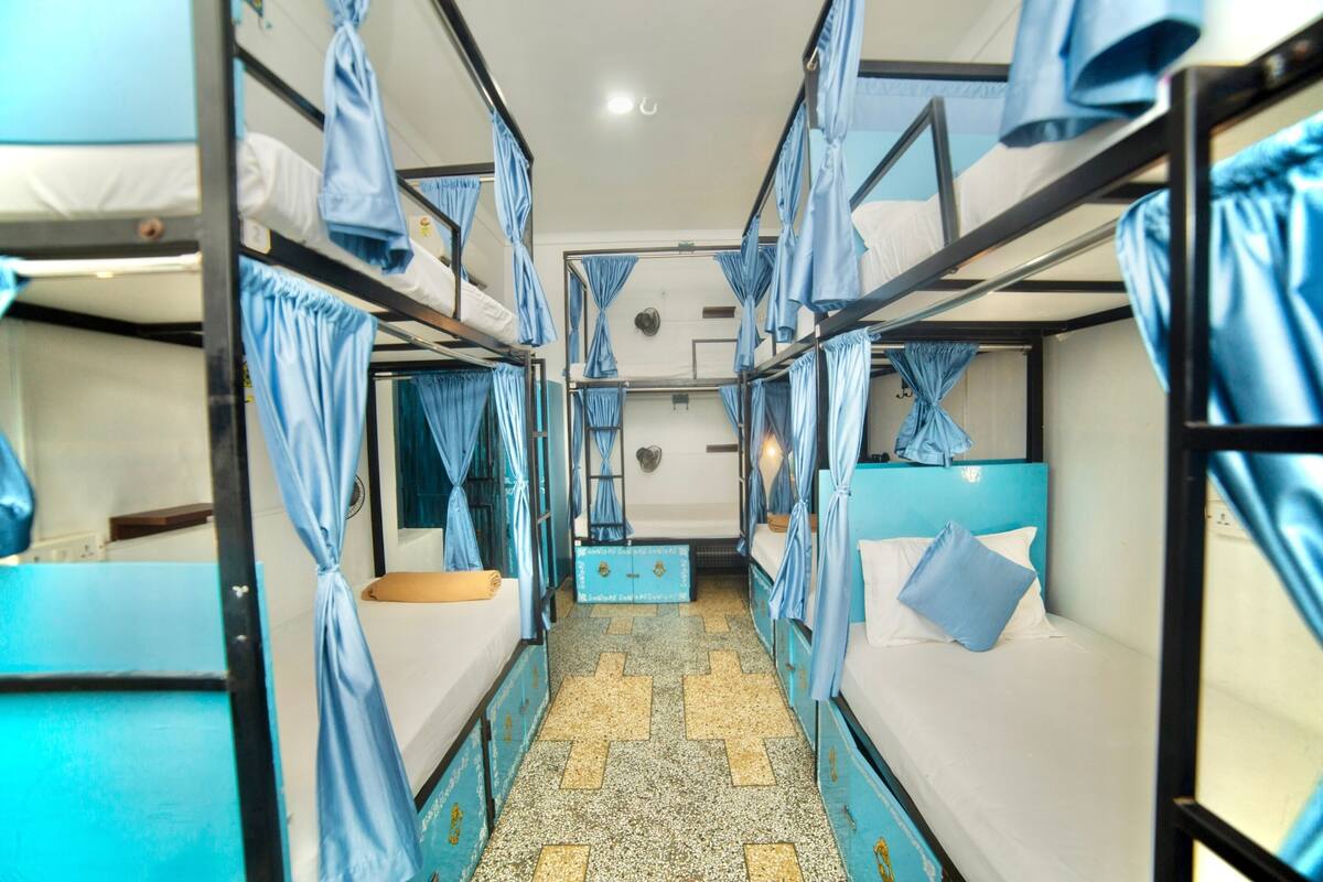 A bunk bed room with curtains, a small table, and a tiled floor.
