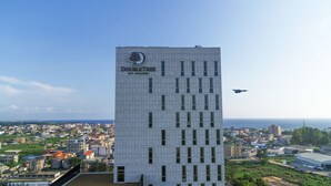 A tall building with the name "DOUBLETREE" and "Y MILTON" on it, surrounded by a cityscape and a clear sky. - Doubletree by Hilton Pointe-Noire (Pointe-Noire)