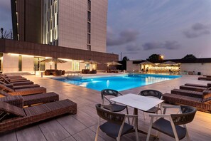 Un espace aménagé au bord de la piscine, avec des chaises longues, une table et des parasols.