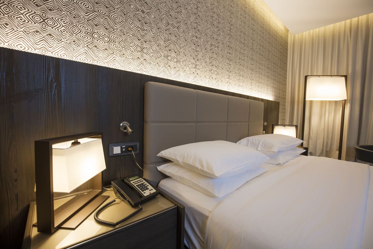 Ein Hotelzimmer mit einem Bett, Nachttischlampen, einem Telefon und einer Wand mit Muster.