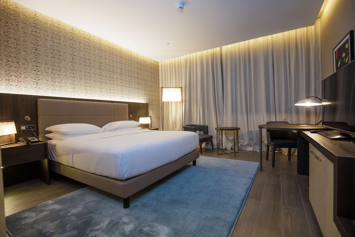 Ein Hotelzimmer mit einem großen Bett, Nachttischen, einem Schreibtisch und einem Stuhl.
