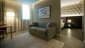 Ein modernes Hotelzimmer mit einer Couch, einem Esstisch und einem Bett.