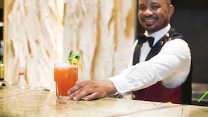 Een bartender maakt een drankje met een rietje en garnering.