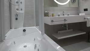 Een moderne badkamer met een douchecabine van glas, een ruim bad en een wastafel met spiegel.