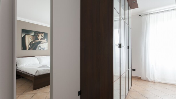 A modern bedroom with a bed, a painting on the wall, and a glass door leading to a bathroom. - Italianway - Vigevano 45 (Milan)