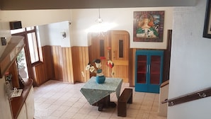 Una habitación amplia con suelo de madera, una mesa con un florero, un banco y una escalera que sube a otro nivel.