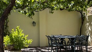 Un patio al aire libre con una mesa, sillas, una planta en maceta y una lámpara de pared.