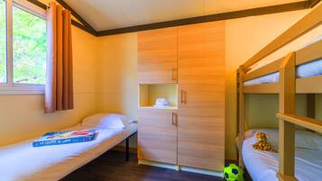 A room with bunk beds, a single bed, a wardrobe, and a window with curtains.