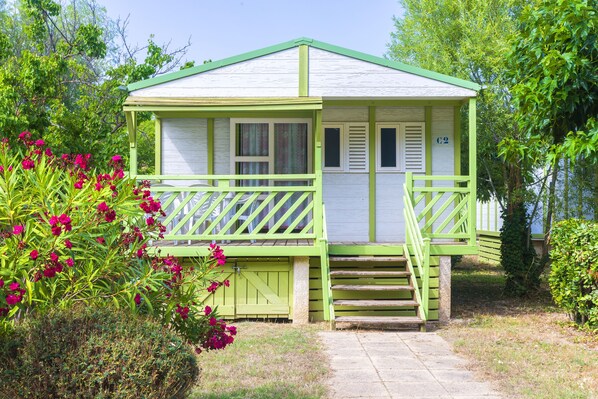 A small, single-story cabin with a green porch and steps leading to the door. - Village Vacances Azureva Sigean (Sigean)