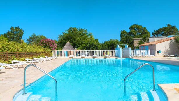A swimming pool with a white fence, lounge chairs, and a small pavilion. - Village Vacances Azureva Sigean (Sigean)