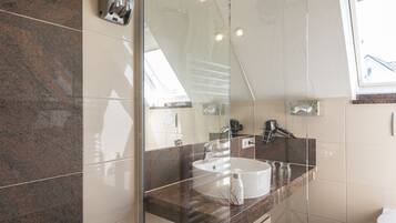 A modern bathroom with a glass shower enclosure, a white sink, and a granite countertop.