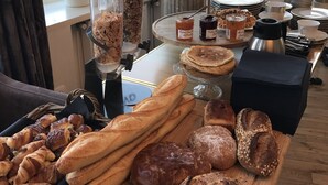 Una mesa de buffet con panes, pasteles y salsas diversas.