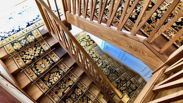 Una escalera de madera con peldaños alfombrados y detallados que conducen a una plataforma.