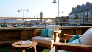 Una terraza en la azotea con mobiliario exterior, vistas panorámicas de la ciudad y farolas.