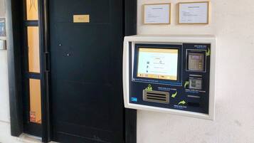 Entrada a una habitación de hotel con una puerta negra, un lector de llave electrónica y dos letreros de bienvenida enmarcados.