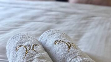 A bed with white linens and gold embroidered text on the foot of the bed.