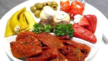 A plate of food with various items including tomatoes, olives, and a green garnish.